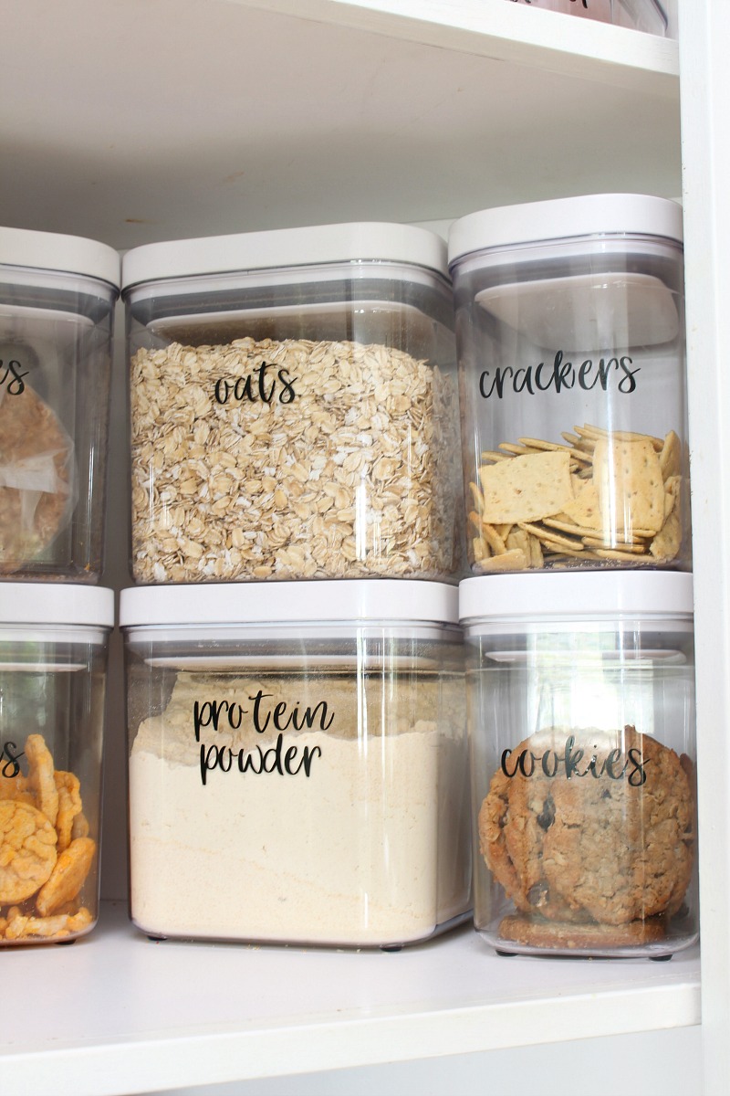 OXO storage bins in a pantry with vinyl labels.