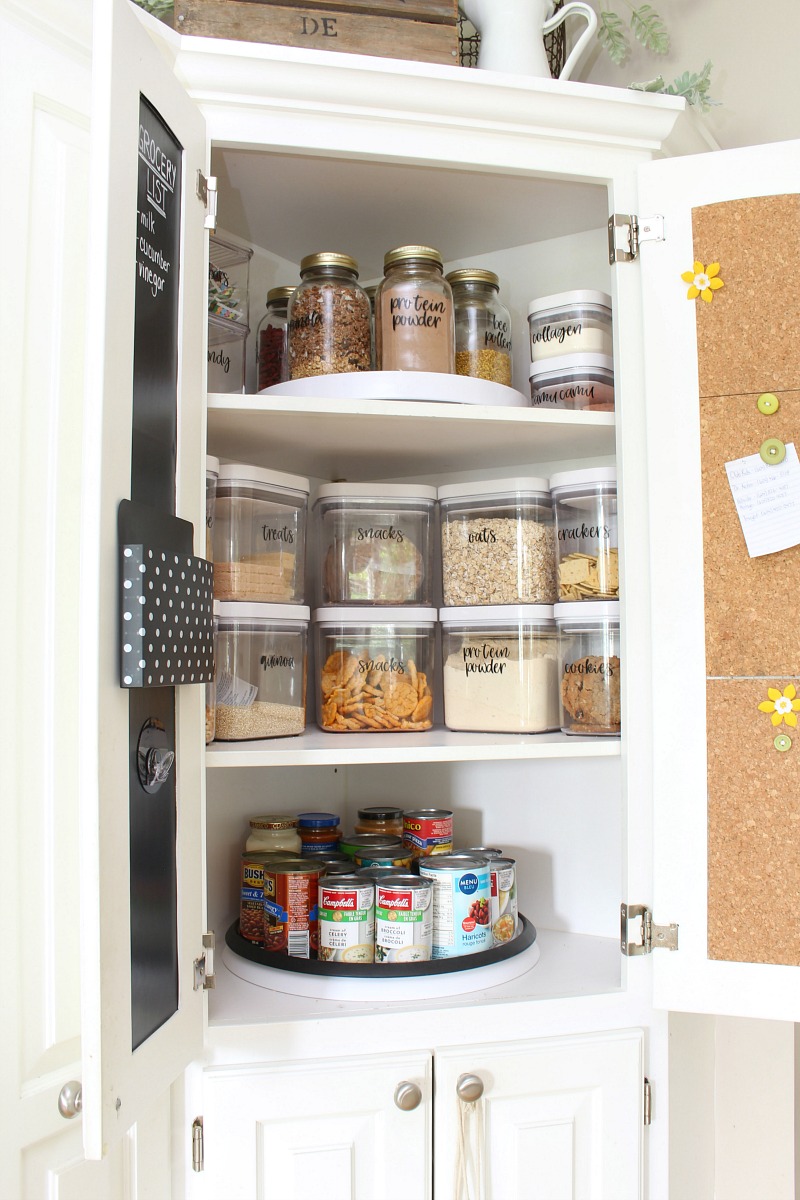 Organized kitchen pantry cupboard with lazy susans and OXO airtight storage containers.
