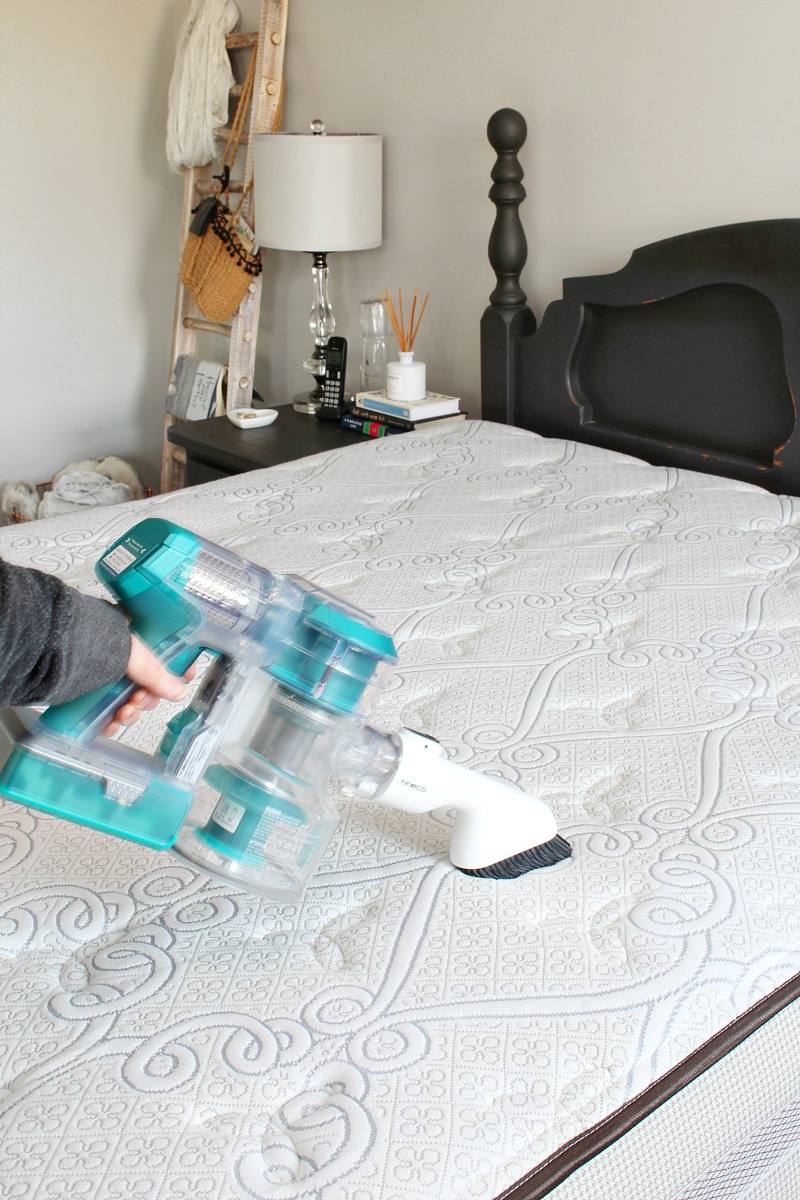 Hand held vacuum cleaning a mattress.