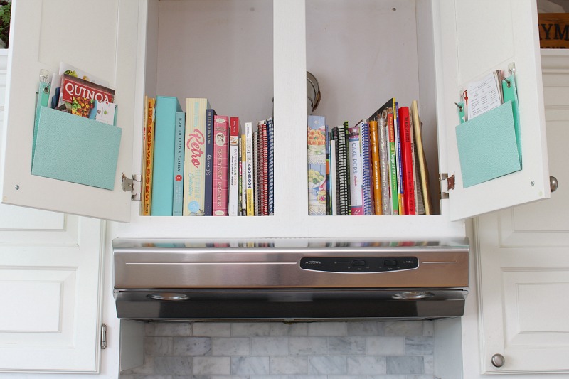 Kitchen cabinet above the stove used for cookbooks.