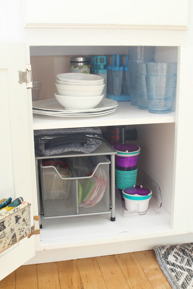 Organized kitchen cupboard for kids' items.
