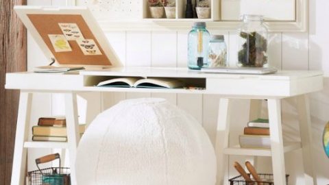 White desk with an exercise ball to sit on.