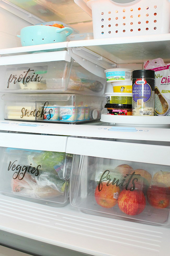 Organized fridge using bins and DIY fridge labels.