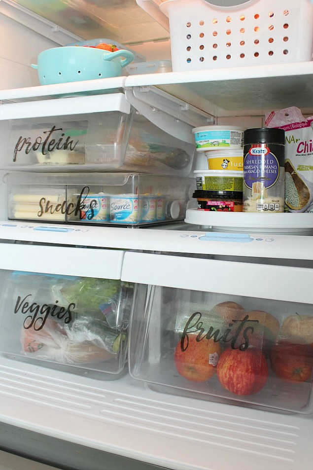 Organized fridge space using bins and free printable fridge labels.