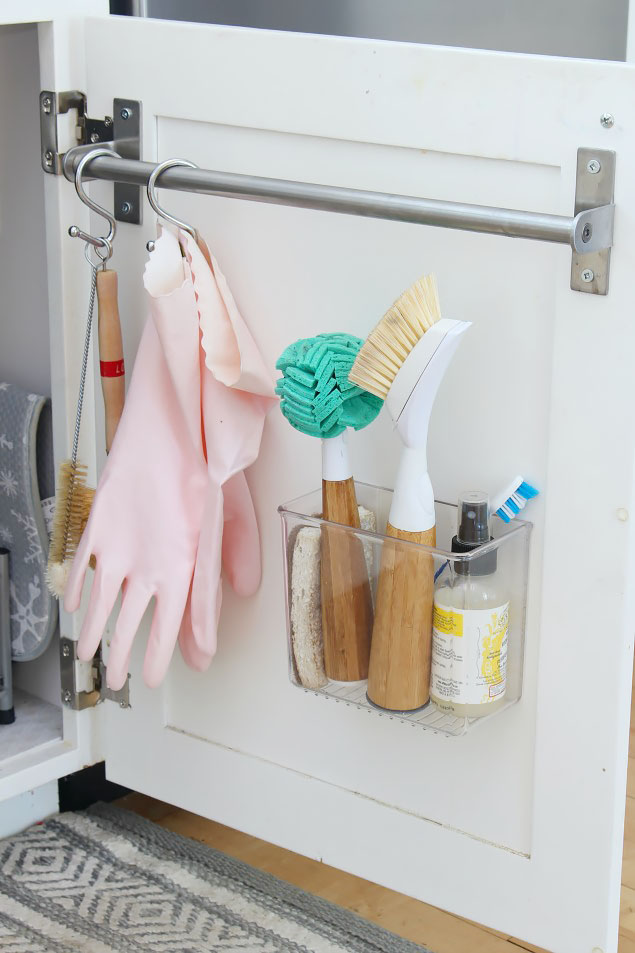 Use the inside of your kitchen cabinet doors for extra storage. White cabinets using a towel bar and adhesive acrylic bin to create extra storage. Great kitchen organization idea!