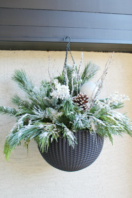 Beautiful Christmas hanging basket with flocked greenery and pinecones.