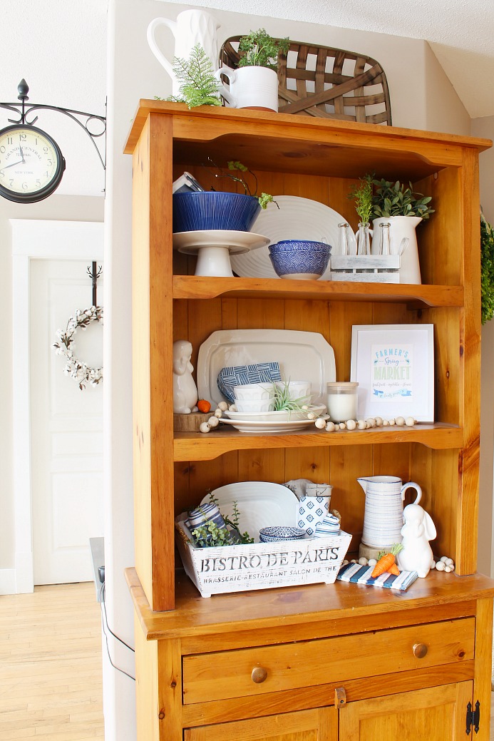 Farmhouse style wooden hutch with white dishes. Styled for spring in with blues and greens.