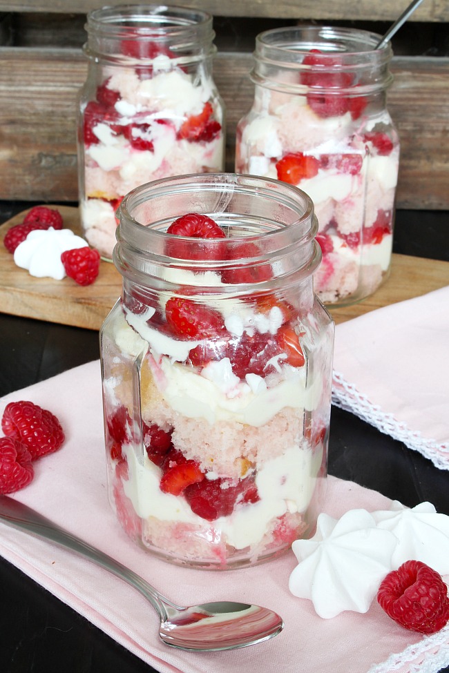 Berry meringue trifle dessert in mason jars. Layers of cake, berries, mascarpone filling, and meringue.