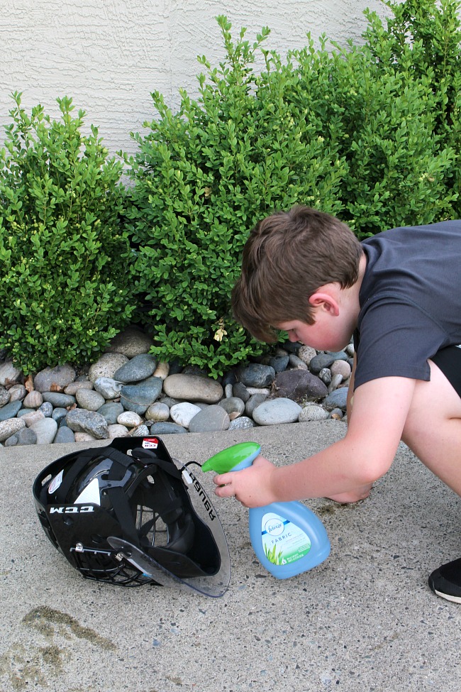 How to Clean Sports Equipment. Boy spraying Febreze on the inside of his goalie helmet.