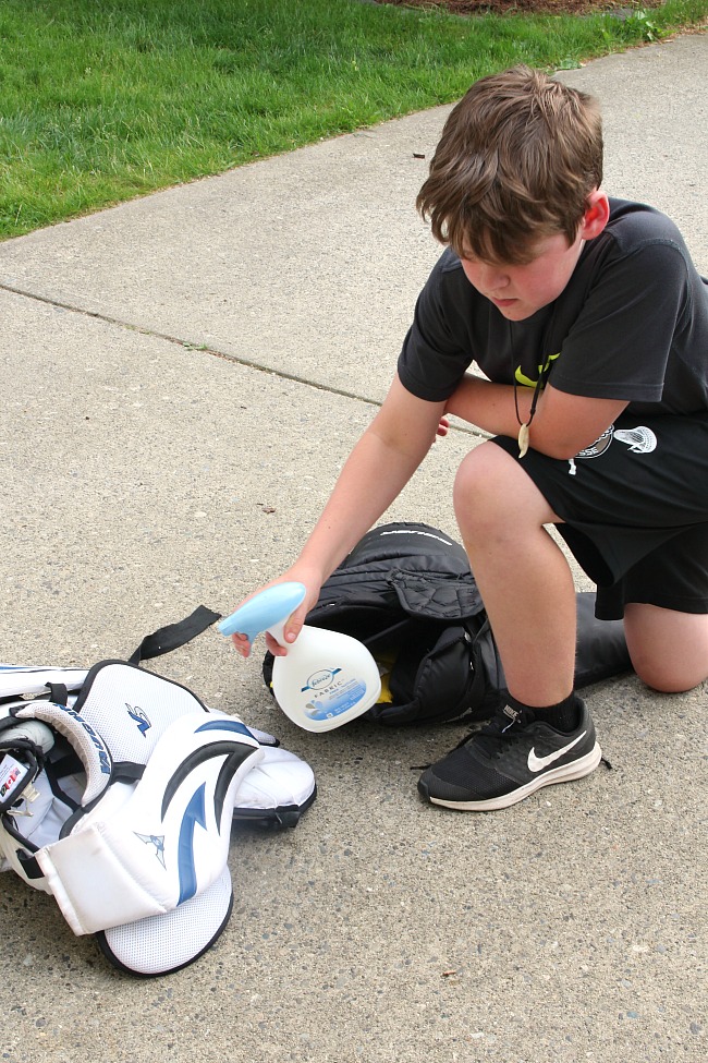 How to Clean Sports Equipment. Boy spraying down sports gear with Febreze.
