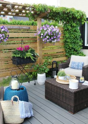 Wooden privacy screen on summer patio decorated with flowers.