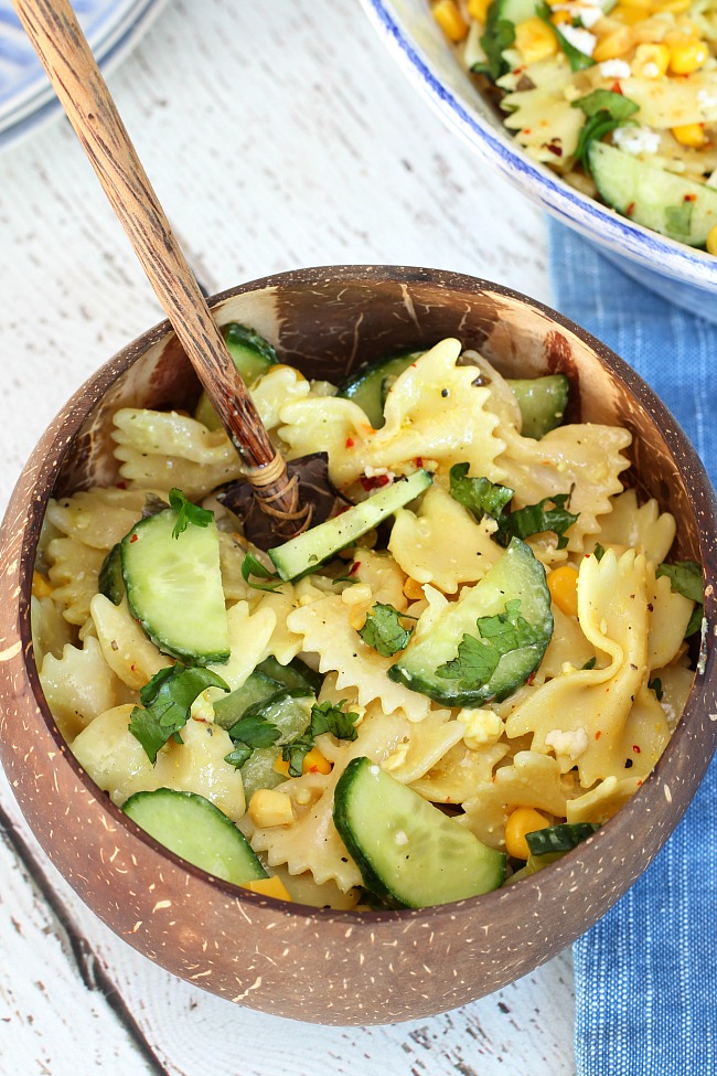 Cucumber and corn pasta salad in a coconut bowl.