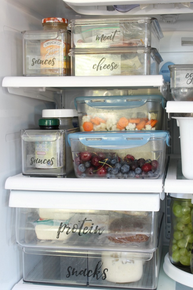 Organized fridge space using clear plastic fridge bins.