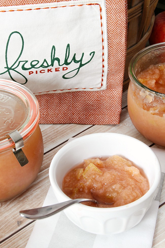 Bowl of homemade applesauce with extra applesauce stored in Weck jars.