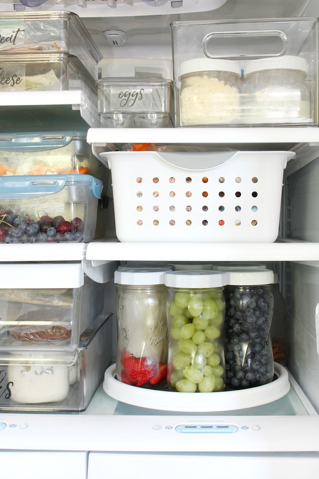 Organized fridge with a lazy susan and mason jars to keep things organized.