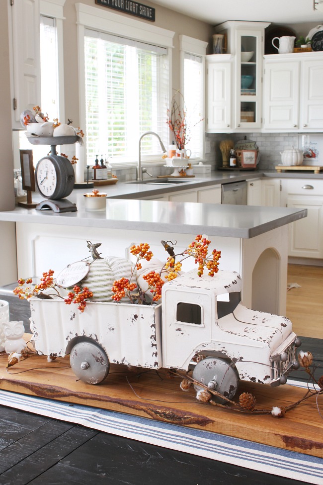 White vintage pick up truck filled with pumpkins and orange berry stems.