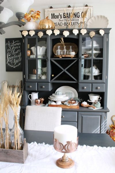 Farmhouse style dining room with painted buffet and hutch. Decorated for fall with neutral colors and natural elements.