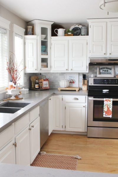 White farmhouse style kitchen decorated for fall with pops of orange.