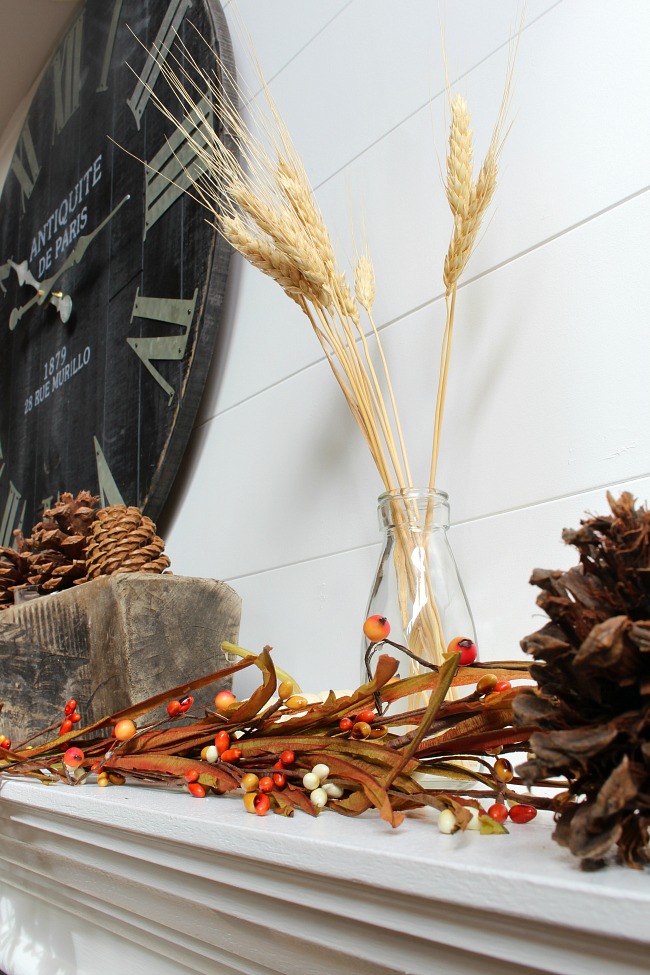 Close up of fall mantel decor with a fall garland, mini-lights and natural elements.