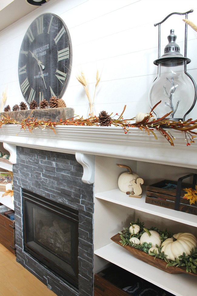 Fall mantel with shelves decorated for fall with white pumpkins.