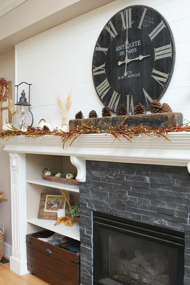 White mantel with dark tile. Decorated for fall with traditional fall colors and natural elements. A weathered wood sugar mold was used in the center.