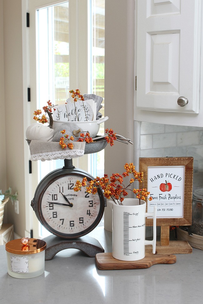 Kitchen scale clock decorated for fall with pumpkins and pops of orange.