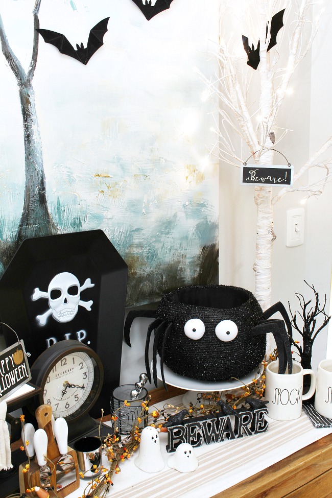 Black and white Halloween decor ideas. Side board decorate with lighted white Christmas trees and black bats.