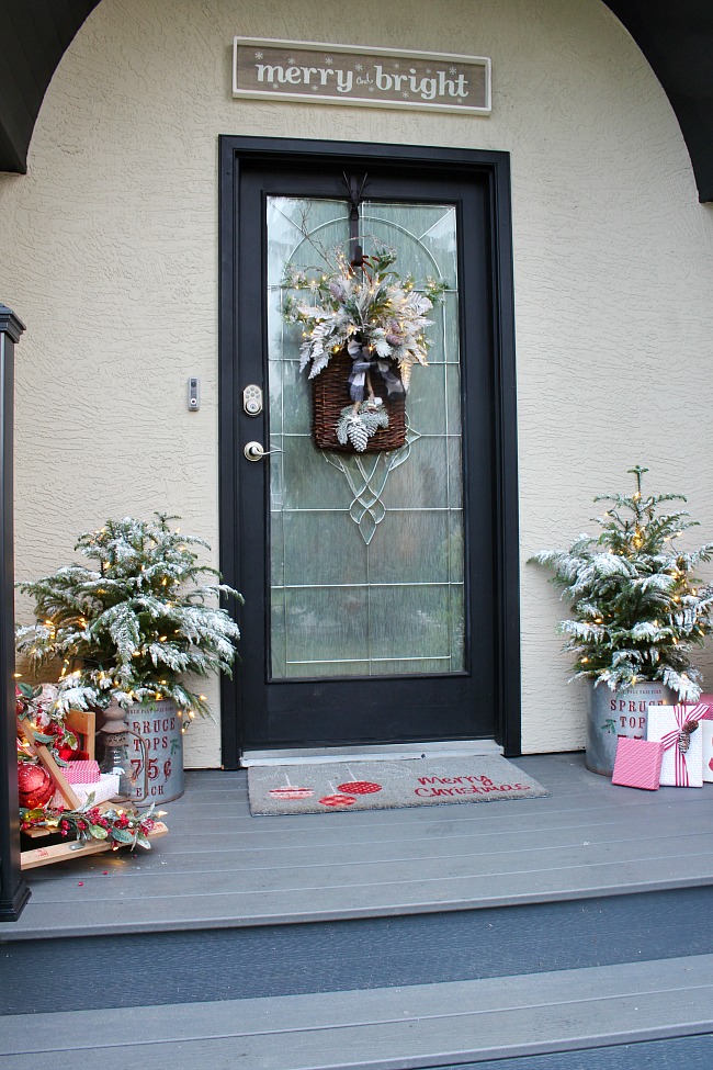 Front porch Christmas decorations with a vintage farmhouse feeling using galvanized Christmas buckets, vintage sleds, and flocked greenery.