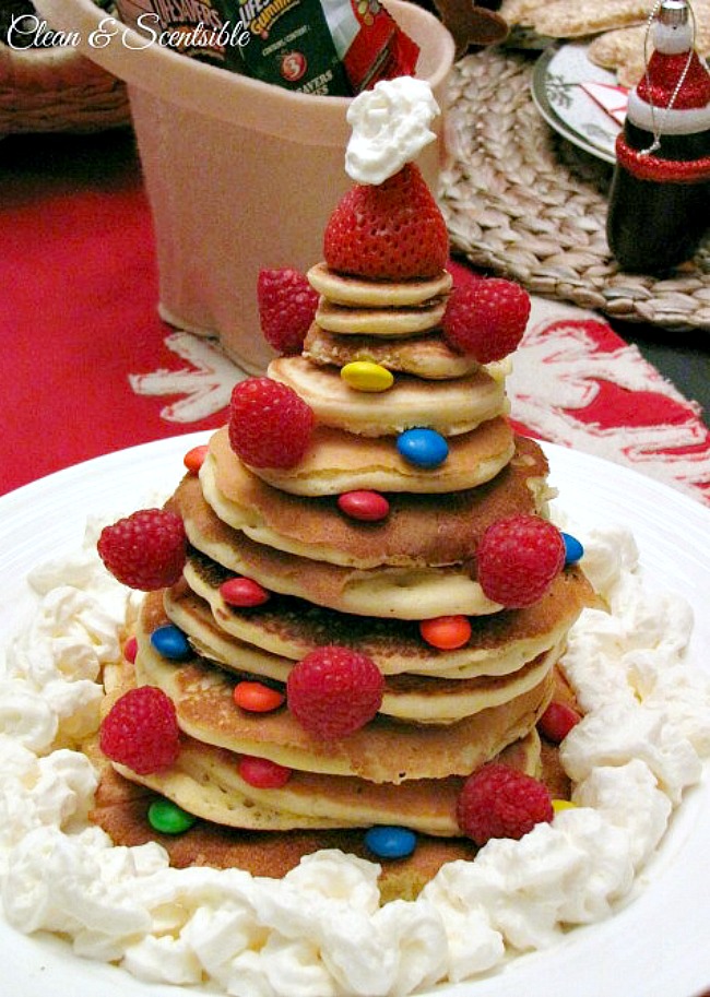 Christmas pancake tree with stacked pancakes and decorated with raspberries and colored candies.