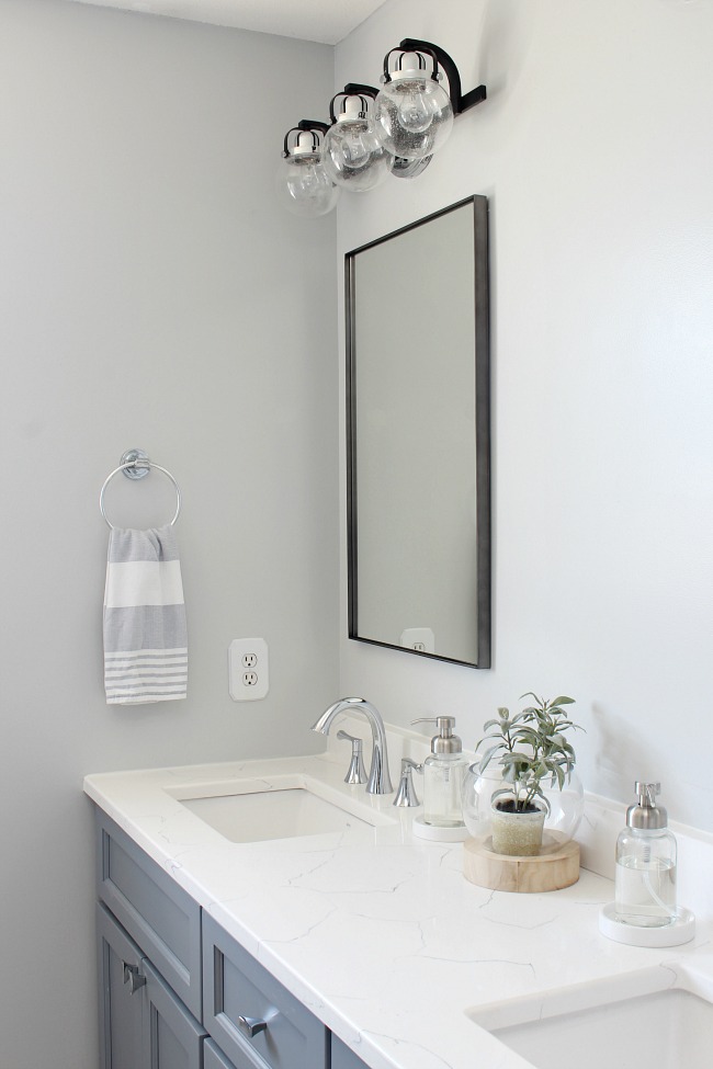 Bathroom vanity with white carerra quartz countertops in a coastal style bathroom.