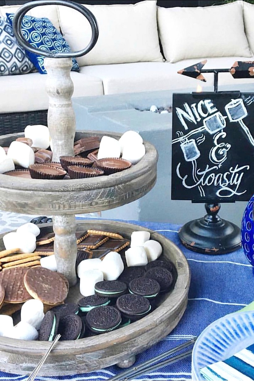 S'mores bar with a variety of cookies and chocolates on a wood tiered tray.