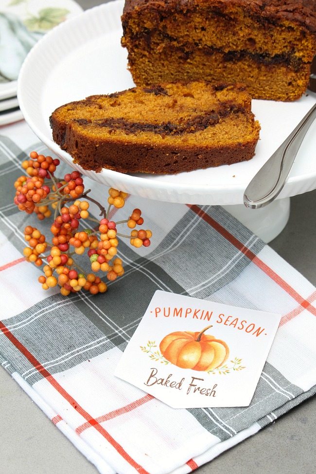 Nutella swirl pumpkin bread on a cake stand with a Baked Fresh fall printable baking tag.