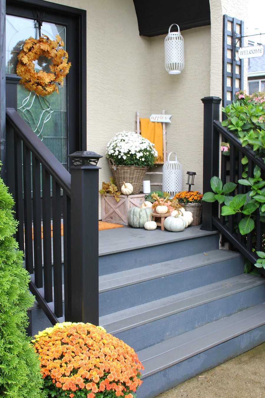 Farmhouse style fall front porch with mums and pumpkins.