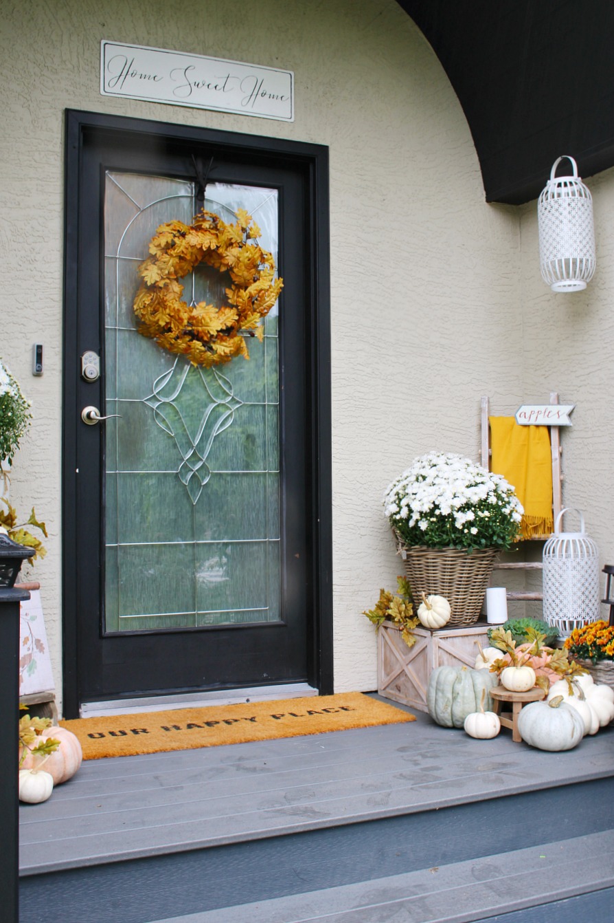 Fall front porch with a blanket ladder, mums and pumpkins.