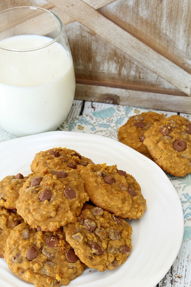 Pumpkin chocolate chip cookies on a plate with a glass of milk.