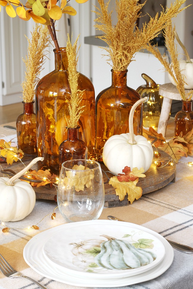 Pretty fall tablescape ideas using amber glass for a centerpiece and fall plates.