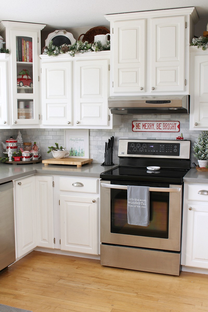 White kitchen decorated for Christmas with greens.