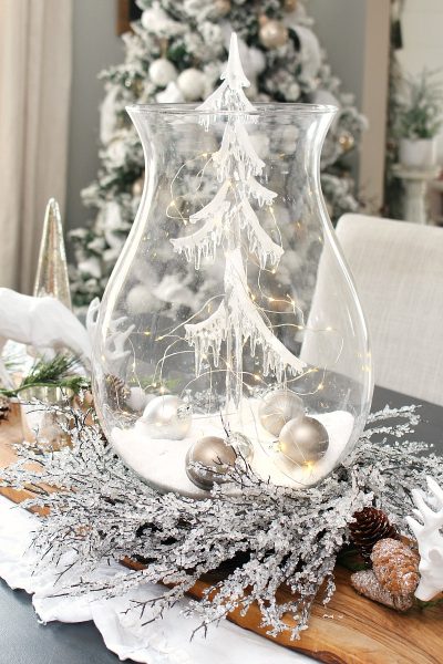 Christmas centerpiece using a large glass candle holder, glass Christmas tree and lights.
