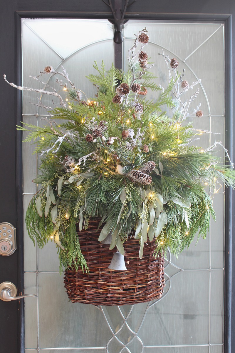 Christmas basket wreath with fresh greenery and fairy lights.