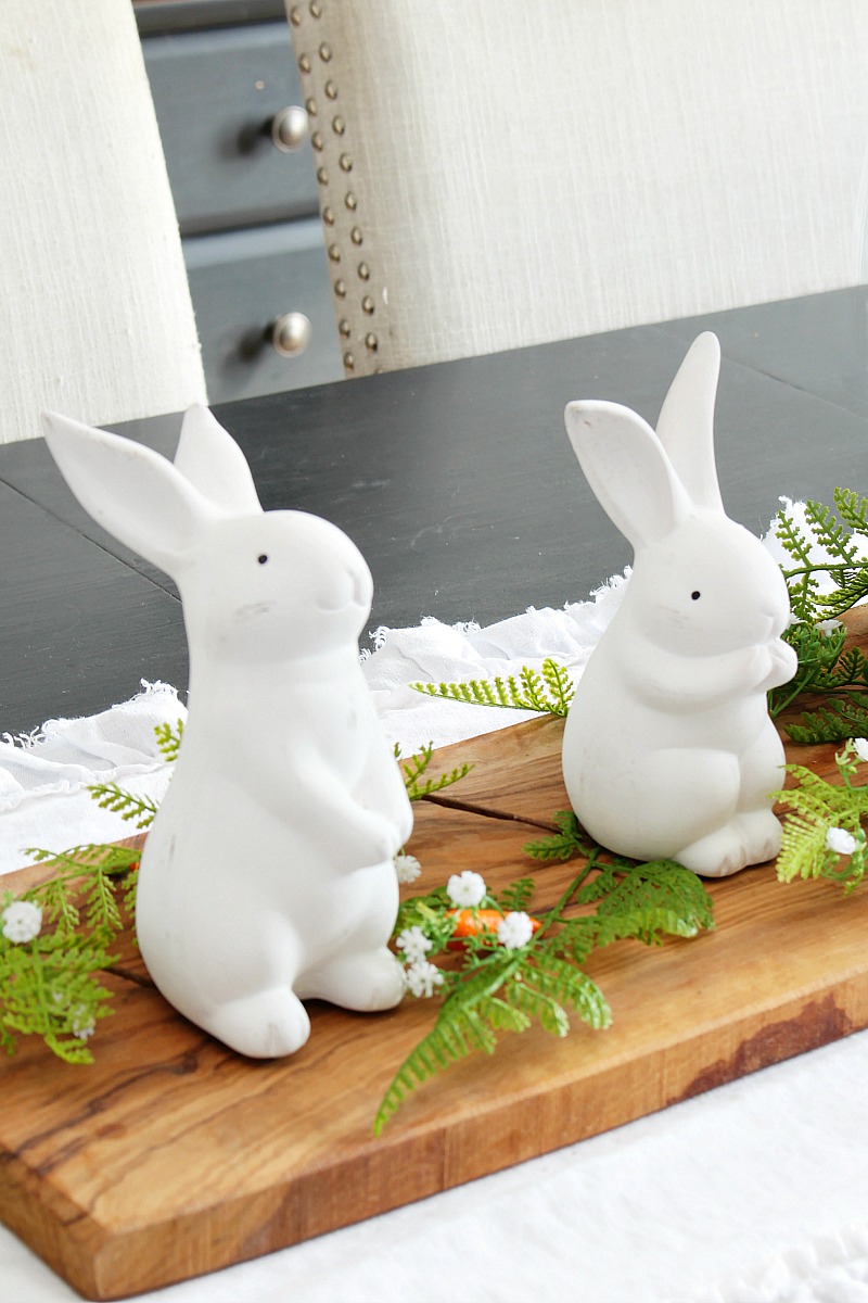 Easter bunny centerpiece with white ceramic bunnies and greenery.