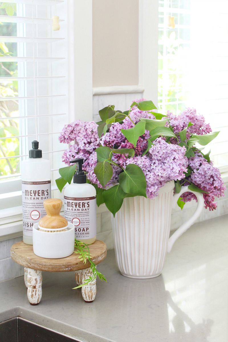 Lilacs in a vase by the kitchen sink.