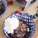 Berry crisp with ice cream in blue bowls.