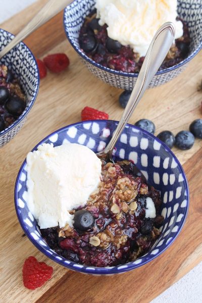 Berry crisp with ice cream in blue bowls.