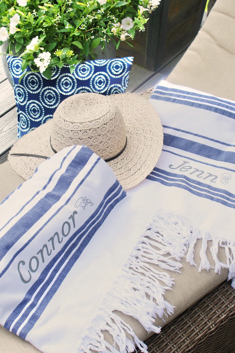 Custom beach towels on a patio lounger with sun hat.