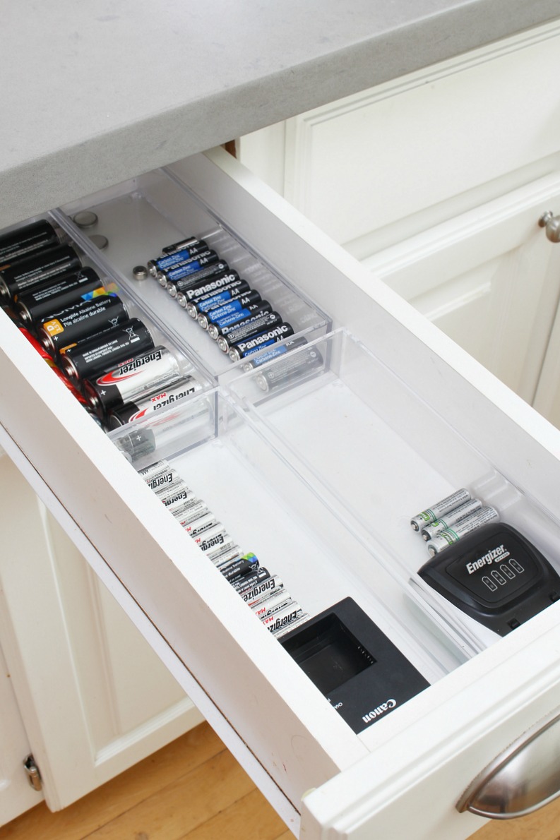 Organized kitchen drawer with batteries stored in acrylic divider bins.