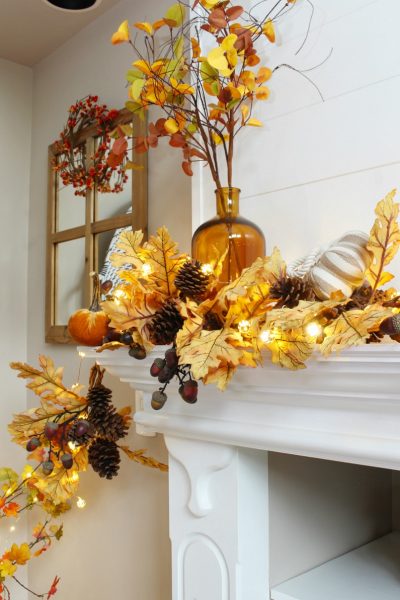 Amber glass vase used on a fall mantel with a golden oak garland and fall lights.