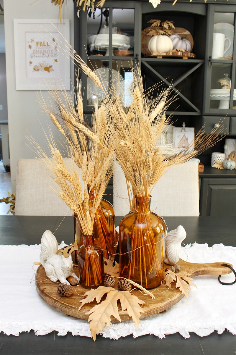 Pretty fall centerpiece with ceramic squirrels and amber glass bottles.