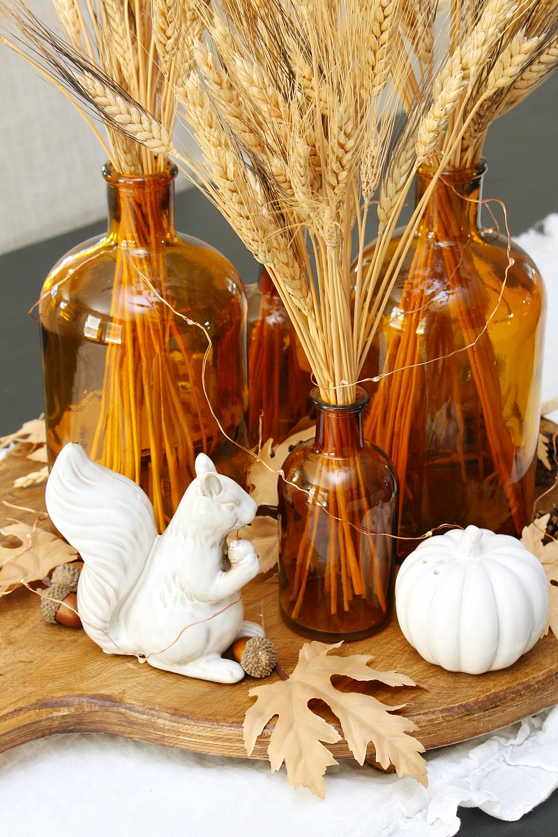 Cute fall centerpiece with glass amber bottles and ceramic squirrels.
