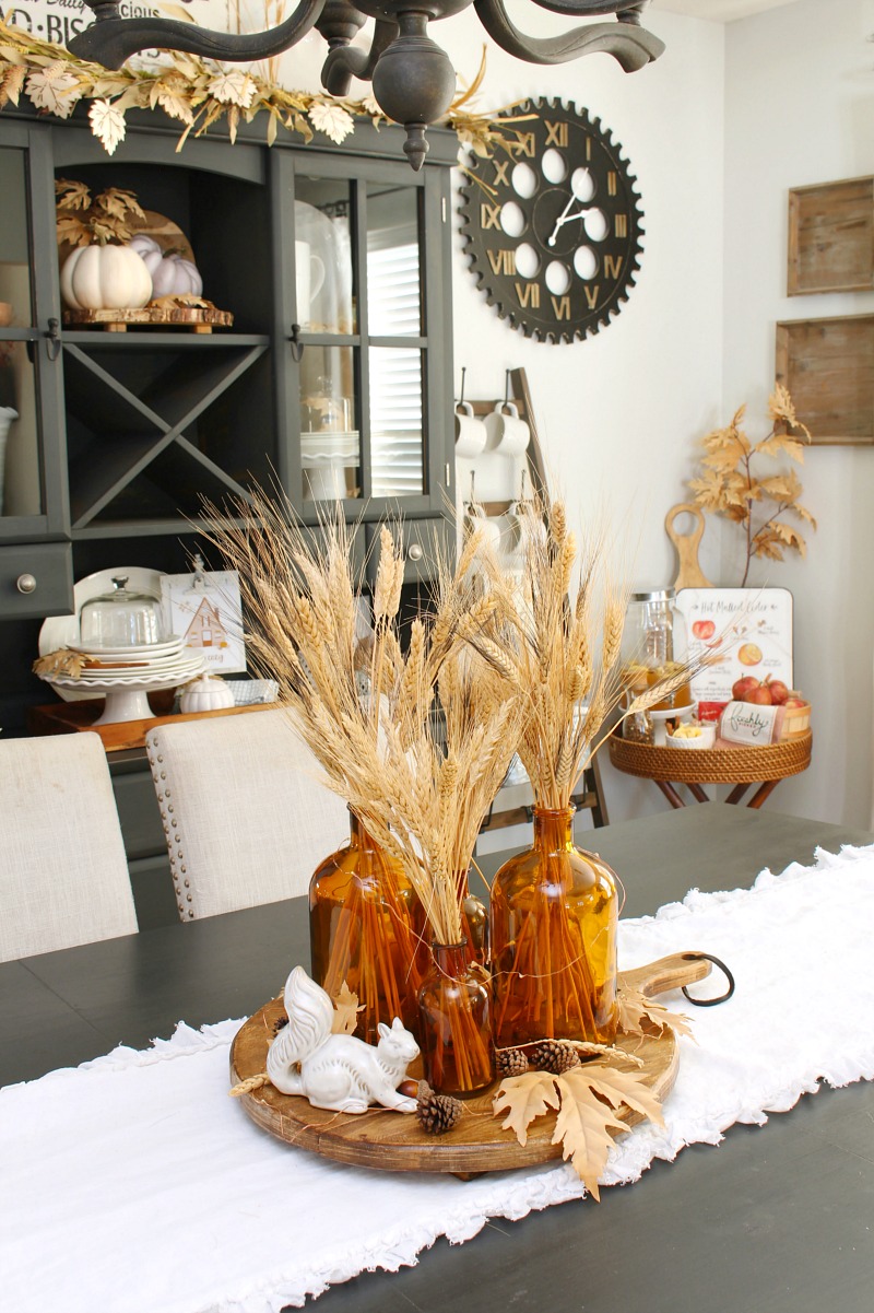 Pretty fall centerpiece with ceramic squirrels and amber glass bottles.
