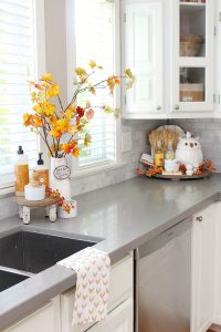 Beautiful farmhouse style white kitchen decorated for fall wth traditional fall colors.